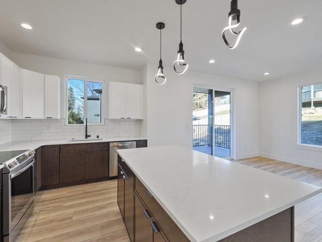 kitchen featuring sink, a center island, dark brown cabinets, stainless steel appliances, and white cabinets