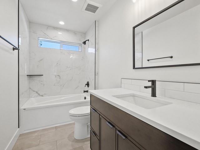 full bathroom featuring tiled shower / bath, vanity, and toilet