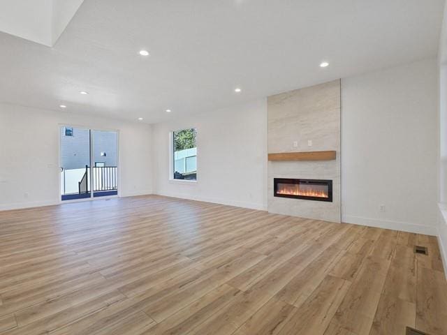 unfurnished living room with a large fireplace and light hardwood / wood-style flooring