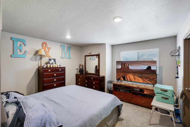 bedroom with light colored carpet and a textured ceiling