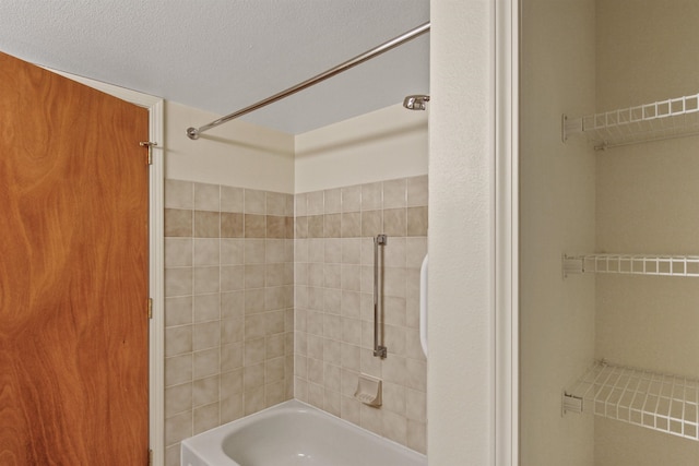 bathroom featuring tiled shower / bath combo and a textured ceiling