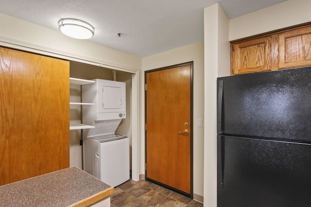 laundry area featuring a textured ceiling and stacked washer / dryer