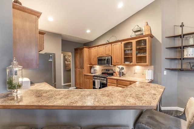 kitchen with stainless steel appliances, lofted ceiling, a kitchen bar, and kitchen peninsula