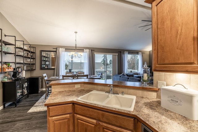 kitchen with sink, backsplash, dark hardwood / wood-style floors, decorative light fixtures, and kitchen peninsula