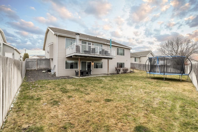 rear view of house featuring a yard, a patio, and a trampoline