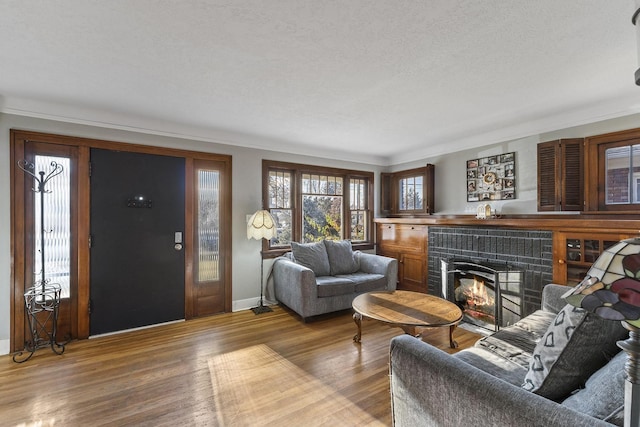 3224 W Cora Ave, Spokane, WA 99205 - living room featuring a brick fireplace, a textured ceiling, baseboards, wood finished floors, and ornamental molding