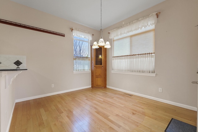 unfurnished dining area with a chandelier and light hardwood / wood-style flooring