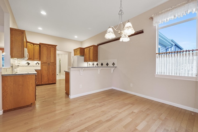 kitchen featuring light hardwood / wood-style floors, a chandelier, white appliances, and kitchen peninsula