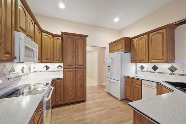 kitchen featuring light wood-type flooring, white appliances, and decorative backsplash