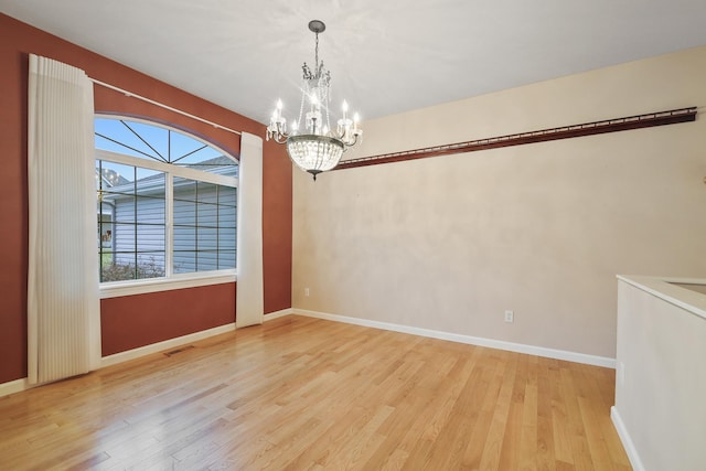 unfurnished dining area featuring an inviting chandelier and light hardwood / wood-style floors