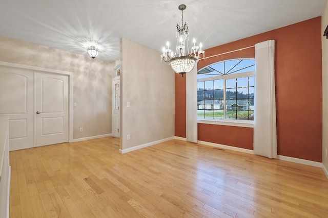 unfurnished dining area with an inviting chandelier and light wood-type flooring