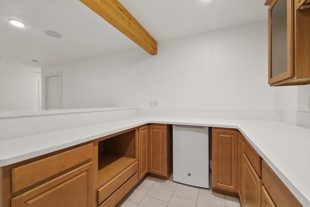 kitchen featuring beamed ceiling, fridge, and light tile patterned floors