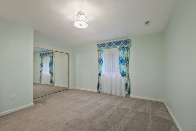 spare room with light colored carpet and a textured ceiling