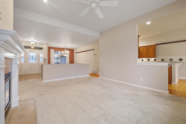 unfurnished living room with ceiling fan with notable chandelier and light carpet