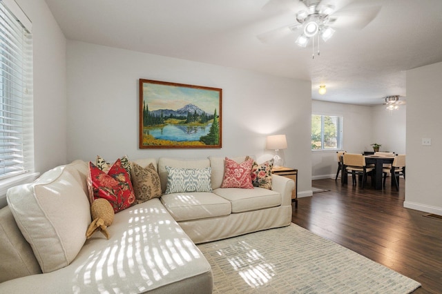 living room featuring dark wood-type flooring and ceiling fan