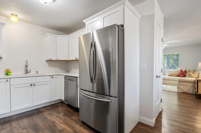 kitchen with sink, a textured ceiling, dark hardwood / wood-style flooring, stainless steel appliances, and white cabinets