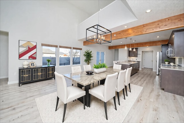 dining space with beamed ceiling, light hardwood / wood-style floors, sink, and a notable chandelier