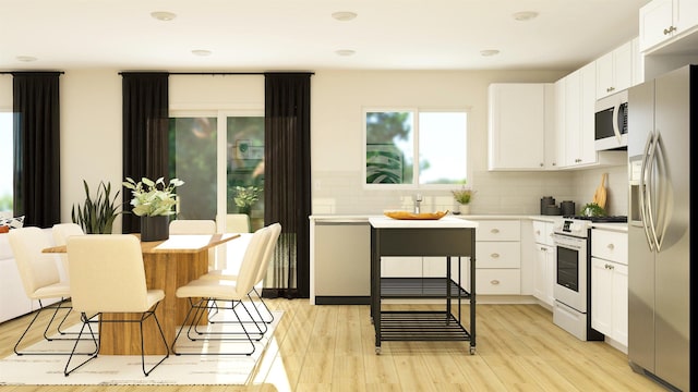 kitchen with tasteful backsplash, appliances with stainless steel finishes, light wood-type flooring, and white cabinets