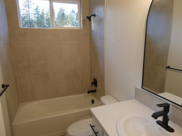 full bathroom featuring tiled shower / bath combo, vanity, and toilet