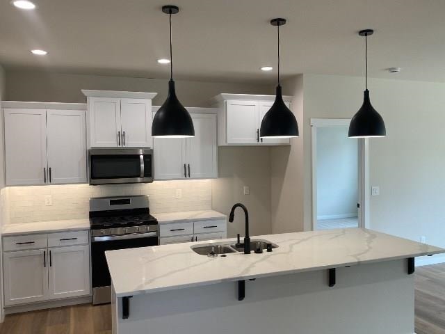 kitchen with light stone countertops, stainless steel appliances, and an island with sink