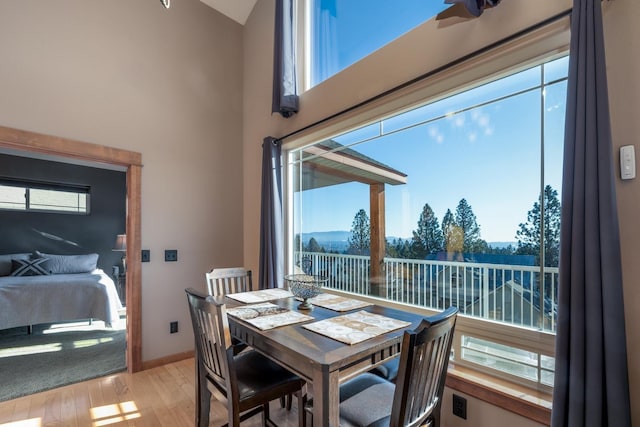 dining space with a wealth of natural light, light hardwood / wood-style flooring, and a towering ceiling