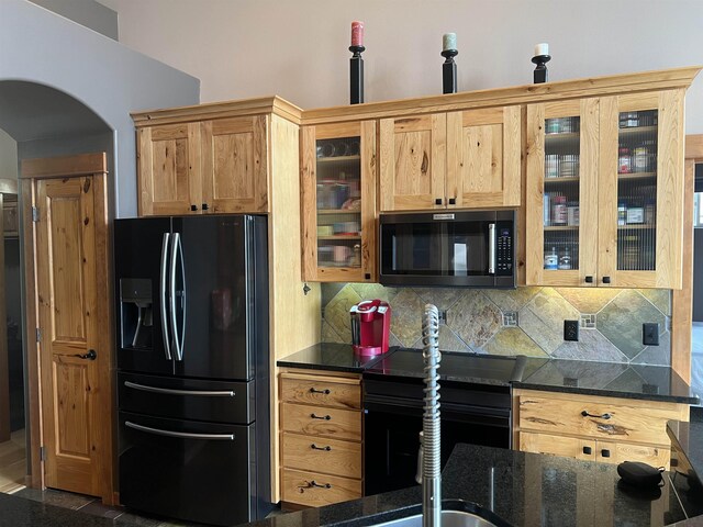 8518 E Sandlewood Ln, Spokane, WA 99217 - kitchen featuring black appliances, arched walkways, backsplash, dark stone countertops, and glass insert cabinets