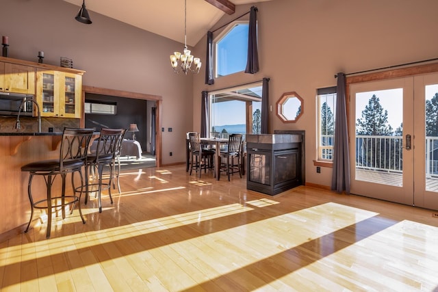 dining room featuring high vaulted ceiling, a chandelier, french doors, beamed ceiling, and light wood-type flooring