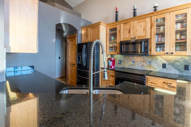 kitchen featuring black fridge with ice dispenser, sink, tasteful backsplash, range with electric stovetop, and dark stone countertops