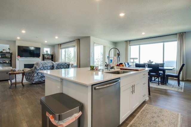 kitchen featuring sink, white cabinets, stainless steel dishwasher, dark wood-type flooring, and a center island with sink