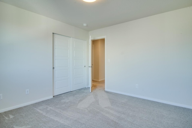 unfurnished bedroom featuring light carpet and a closet