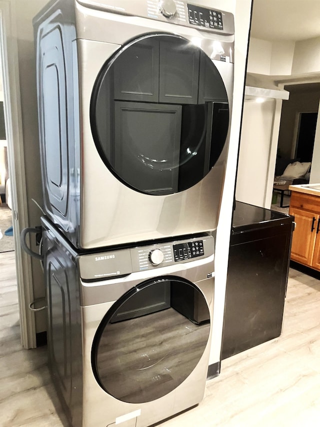 laundry room featuring stacked washer / drying machine and light hardwood / wood-style flooring