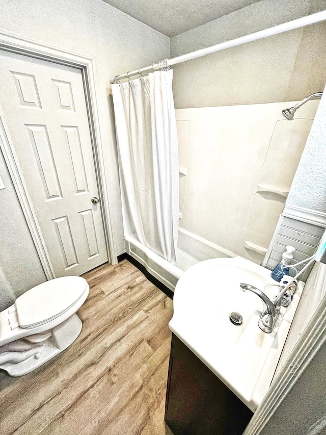 bathroom featuring hardwood / wood-style floors, shower / bath combination with curtain, and toilet