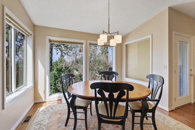 dining area with a textured ceiling, a notable chandelier, and light hardwood / wood-style floors