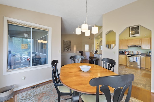 dining area featuring vaulted ceiling and light hardwood / wood-style flooring