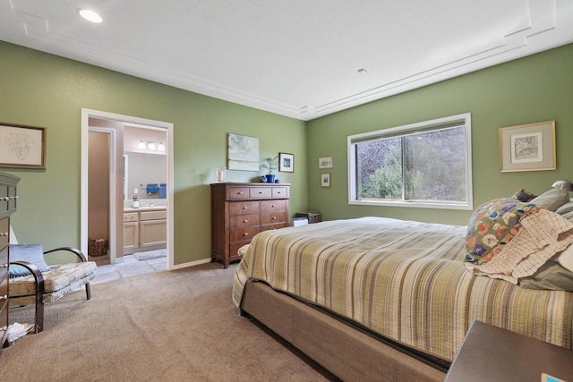 bedroom featuring connected bathroom and light colored carpet