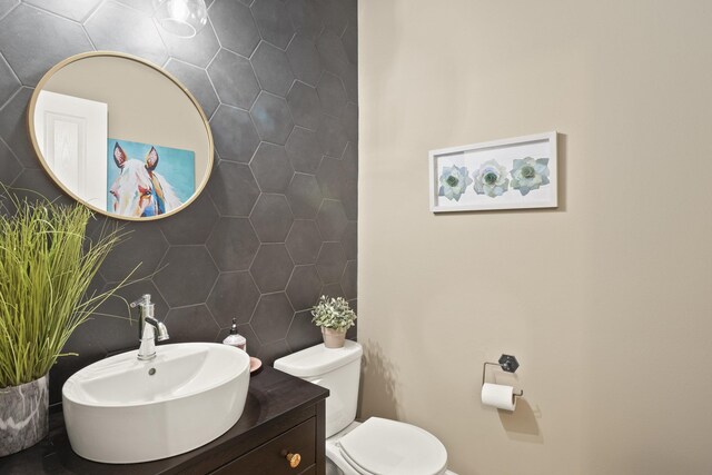 half bath with vanity, toilet, and tile walls