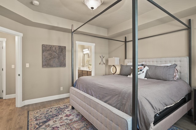 bedroom with baseboards, wood finished floors, and ensuite bathroom