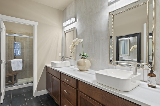 full bathroom with a stall shower, double vanity, tile patterned flooring, and a sink