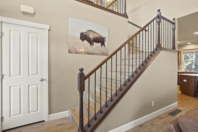 stairway with baseboards, visible vents, wood finished floors, and recessed lighting