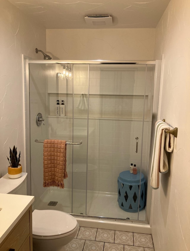 bathroom featuring tile patterned flooring, toilet, visible vents, vanity, and a shower stall