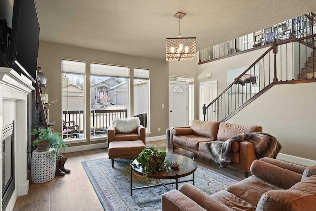 living room featuring baseboards, a textured ceiling, stairway, and wood finished floors