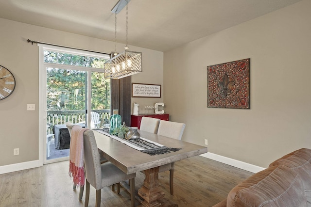 dining space with baseboards, wood finished floors, and an inviting chandelier