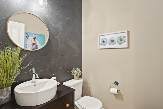 half bath with toilet, vanity, and tile walls