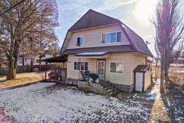 snow covered rear of property featuring a carport and a porch