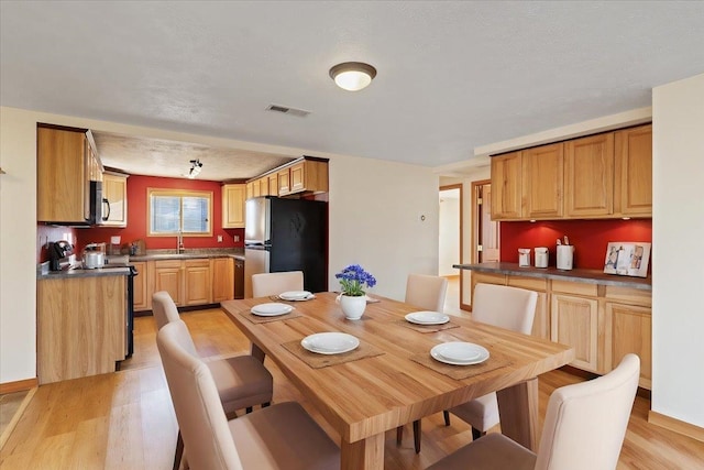 dining space with sink, a textured ceiling, and light hardwood / wood-style floors