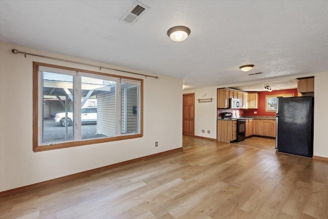 kitchen with fridge, black electric range, light hardwood / wood-style flooring, and a textured ceiling