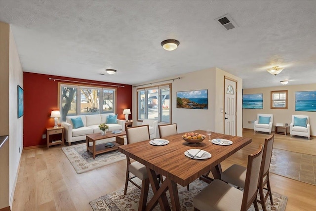 dining area featuring a textured ceiling and light wood-type flooring