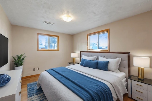 bedroom with hardwood / wood-style flooring, multiple windows, and a textured ceiling