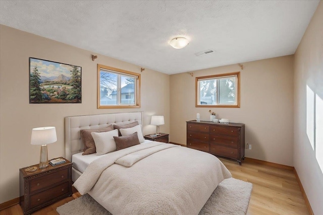 bedroom featuring light hardwood / wood-style flooring and a textured ceiling