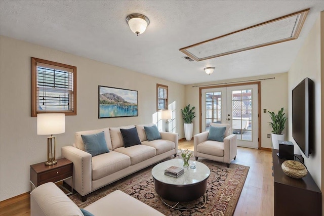 living room with hardwood / wood-style floors, a textured ceiling, and french doors